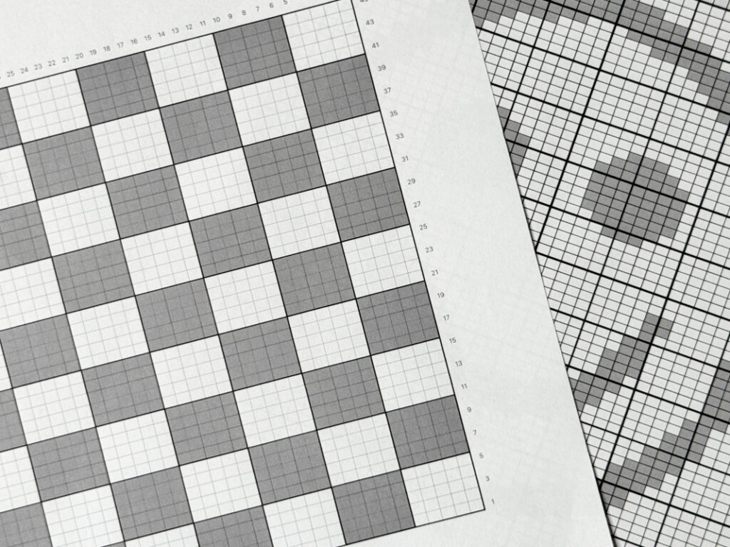 Nahaufnahme zweier Strickcharts mit weißen und grauen Kästchen