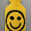 gestrickte Wärmflaschenhülle in gelb mit schwarzem lachenden Smiley in Double Knitting