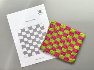 Strickchart neben einem fertigen Double-Knitting-Topflappen in