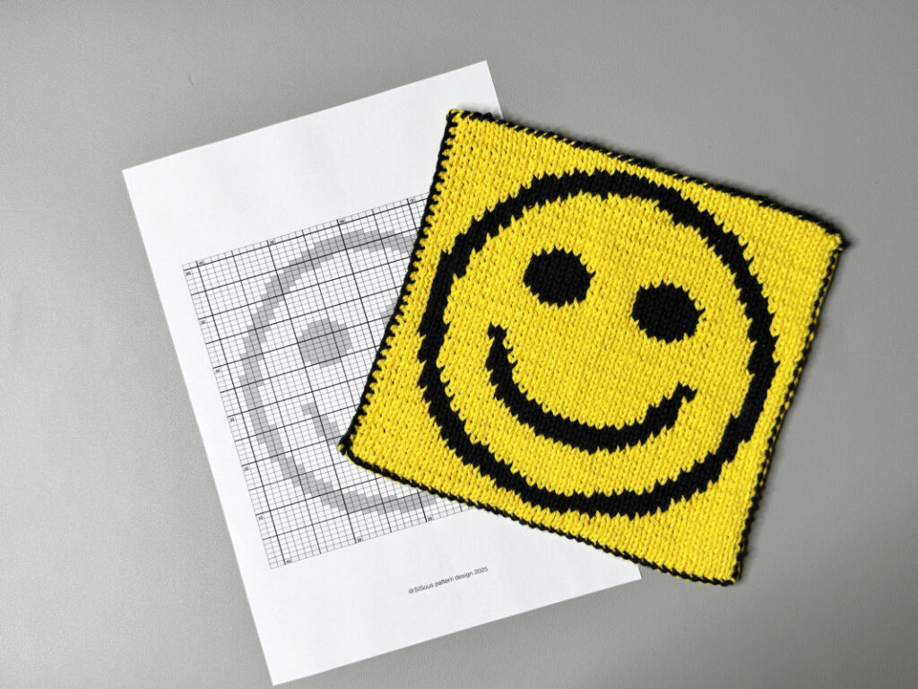 Strickchart neben einem fertigen Double-Knitting-Topflappen in Smiley-Optik