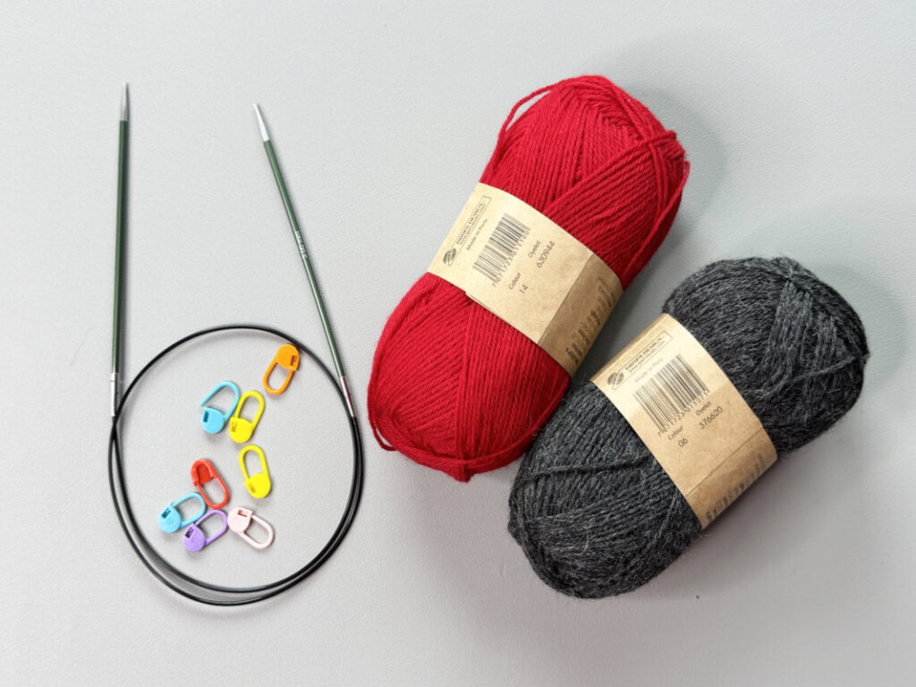 Flatlay mit Garn, Rundstricknadel und Maschenmarkierer für Double Knitting